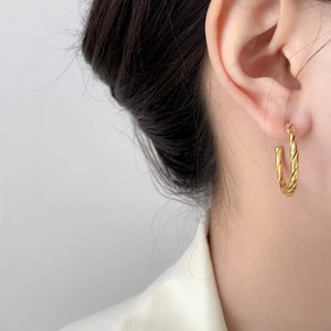 Detail of gold twisted rope hoop earrings featuring textured 18K plated stainless steel