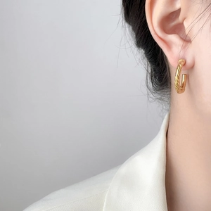 Detailed view of C-shaped twisted gold earrings with textured rope design on model