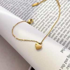 Detail of a polished gold heart pendant on a delicate chain over book pages