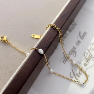 Detail of gold snake chain bracelet with freshwater pearls and a heart pendant