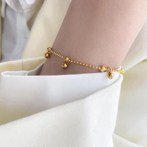 Elegant gold beaded chain bracelet with five polished spheres on minimalist white sleeve