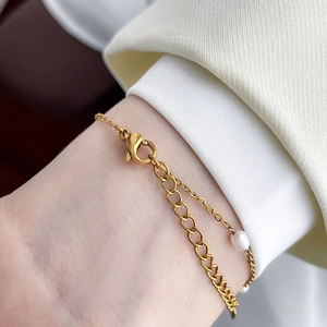 Detailed view of a gold heart pendant bracelet with pearls and lobster clasp on wrist