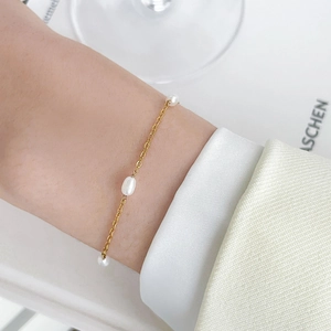 Detailed shot of gold plated snake chain bracelet with white freshwater pearls on wrist