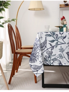 Close-up of linen-style tablecloth featuring elegant blue floral and bird embroidery art