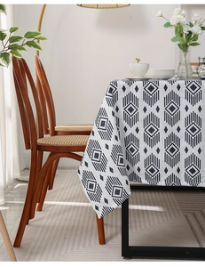 Detail of ivory rectangular tablecloth with black geometric diamond patterns on a wooden table