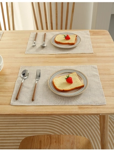 Detailed close-up of light beige linen-textured rectangular placemat on a wooden table