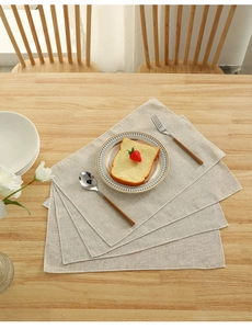 Linen placemat set on a wooden table with ceramic plate and rustic breakfast setting