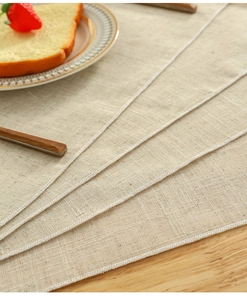 Close-up of beige linen textured placemat showing fine stitching on a wooden table