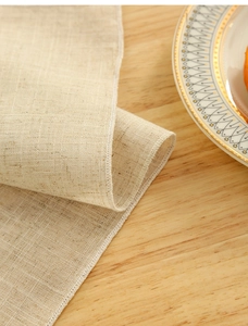 Detail of beige polyester table mat showing plain weave texture and white stitched edges