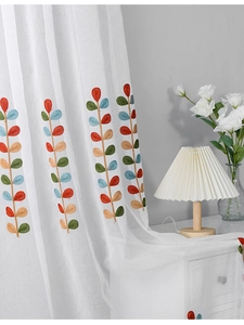Detail of white sheer curtain featuring colorful leaf embroidery in Nordic minimalist style