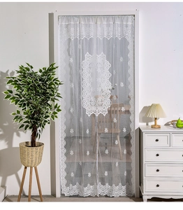 Detail of white French lace door curtain with floral embroidery and scalloped edges