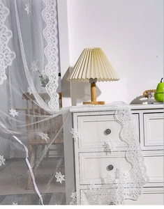 Close-up of white French lace curtain with delicate star embroidery and scalloped edges
