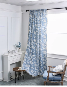 Detail of light blue floral curtain with white mandala print and beige tassel fringe