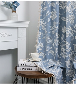 Detail of light blue Nordic curtain with white floral patterns and tassel edges
