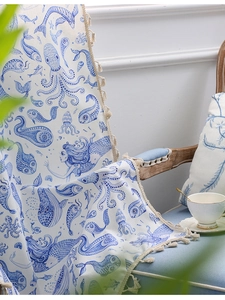 Close-up of ocean-themed throw blanket with blue octopus prints and fringe detail