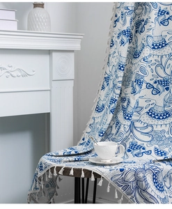 Detail of blue and white fox print curtain fabric with elegant white fringe trim