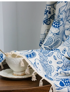 Detail of blue floral curtain fabric with cat print and off-white decorative tassels