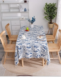 Close-up of blue and white linen tablecloth with artistic floral patterns and tassels