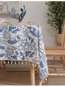 Detail of blue and white linen tablecloth featuring llama illustration and cotton tassels