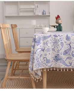 Close-up of linen tablecloth with blue ocean mermaid print and cream tassel edges