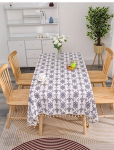 Close-up of linen tablecloth featuring geometric diamond patterns and tassel edge detail