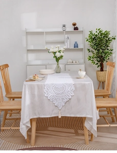 Detail of white lace table runner with intricate floral crochet patterns and tassel fringe