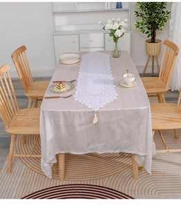 Detail of champagne satin tablecloth and white lace table runner with fringe tassels