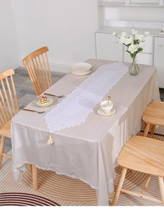 Detailed view of white floral lace table runner with elegant handmade fringe tassels