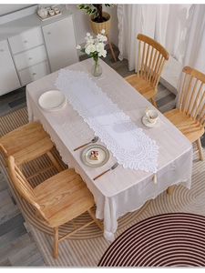 Detail showing off-white lace table runner with intricate hollow patterns and tassels