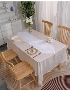Close-up of elegant white European lace table runner with floral patterns and tassels