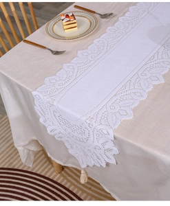 Detail of white lace table runner with hollow floral pattern and elegant fringe edges