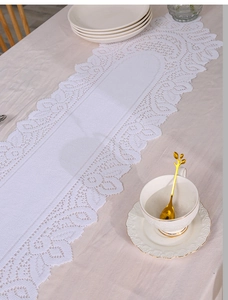 Close-up of white lace table runner featuring delicate crochet patterns and wavy edges