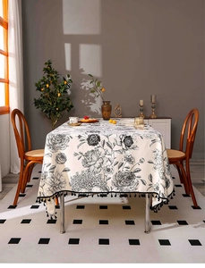 Detail of oil-proof cotton linen tablecloth with black floral patterns and tassel edges