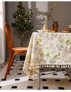 Detail of linen tablecloth with green leaf patterns and elegant beige tassel fringe edge