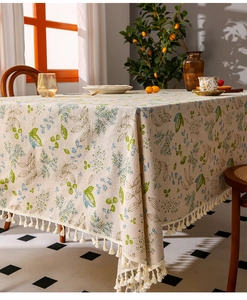 Detail of floral linen tablecloth featuring elegant white tassels and natural fabric texture
