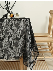 Close-up of black lace tablecloth with pumpkin and spider web patterns for Halloween