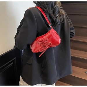 Detail of red patent leather shoulder bag with corset-style lacing and bow decoration