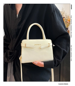 Détail d'un sac à main crème minimaliste avec garnitures dorées et logo gravé