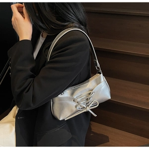 Close-up of silver ballet-style shoulder bag with decorative ribbons and bow detailing
