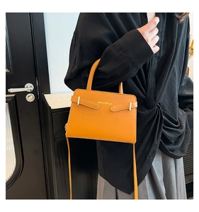 Détail du sac bandoulière jaune gingembre avec poignée et boucle argentée sur modèle