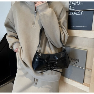 Detail of glossy black shoulder bag with stylish lacing element and silver zipper