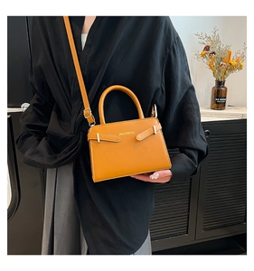 Détail du sac bandoulière jaune moutarde avec boucle en métal et bandoulière sur un modèle