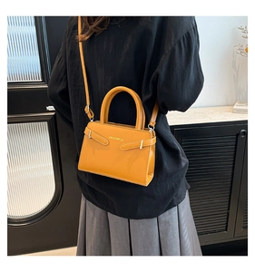 Gros plan du sac à main jaune en cuir avec boucle métallique porté par un mannequin