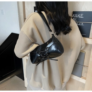 Close-up of a black glossy leather shoulder bag with chic lace-up corset style details