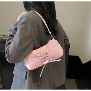 Pink pleated underarm bag featuring ballet-inspired corset lacing and bow details