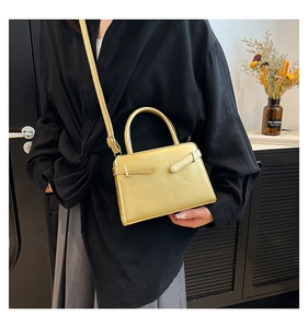Détail d'un sac à main doré en cuir verni avec des lanières à boucles métalliques
