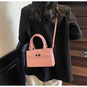 Pink crocodile pattern shoulder bag with silver buckle worn over a black blazer