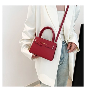 Vue détaillée du sac à main rouge élégant avec logo métallique porté par un modèle
