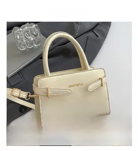 Détail du sac bandoulière crème avec sangle réglable et boucles métalliques latérales