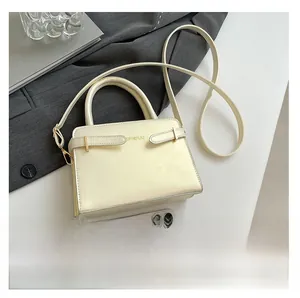 Détail du petit sac carré crème avec logo doré SPINPIJU et smartphone pour l'échelle de taille